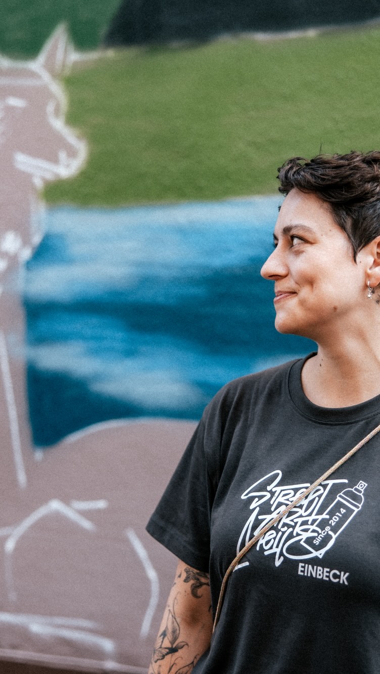 dunkelhaarige junge Frau vor Streetart