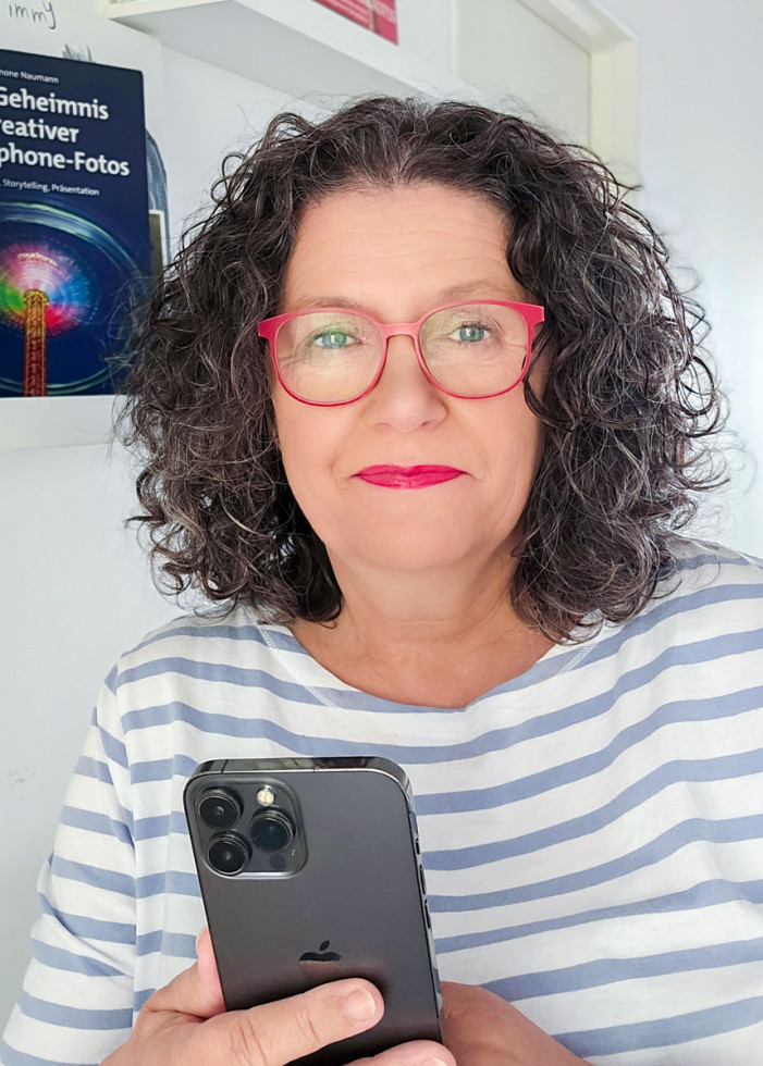 Simone Naumann, Porträtaufnahme, rote Brille, passender Lippenstift, Streifentop, lockiges grau meliertes Haar