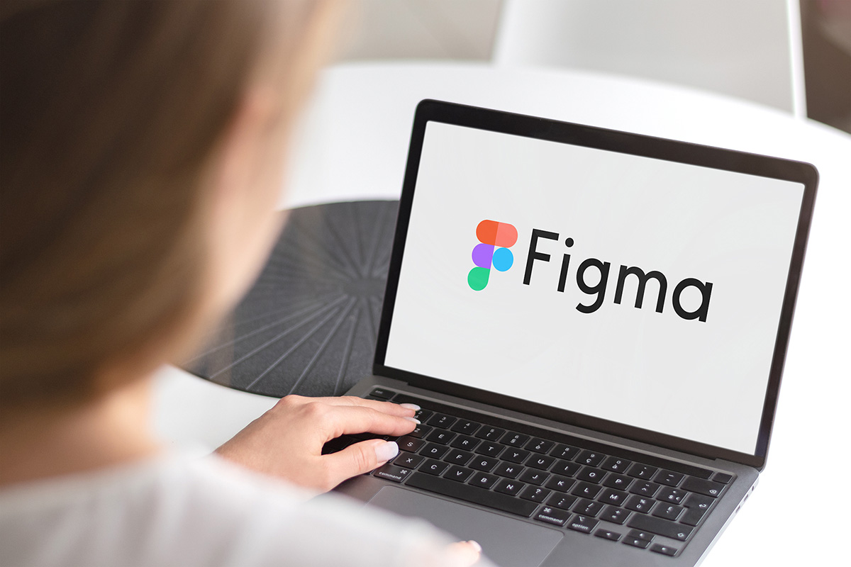 Over-Shoulder Aufnahme einer jungen Frau am Bildschirm mit Figma Logo